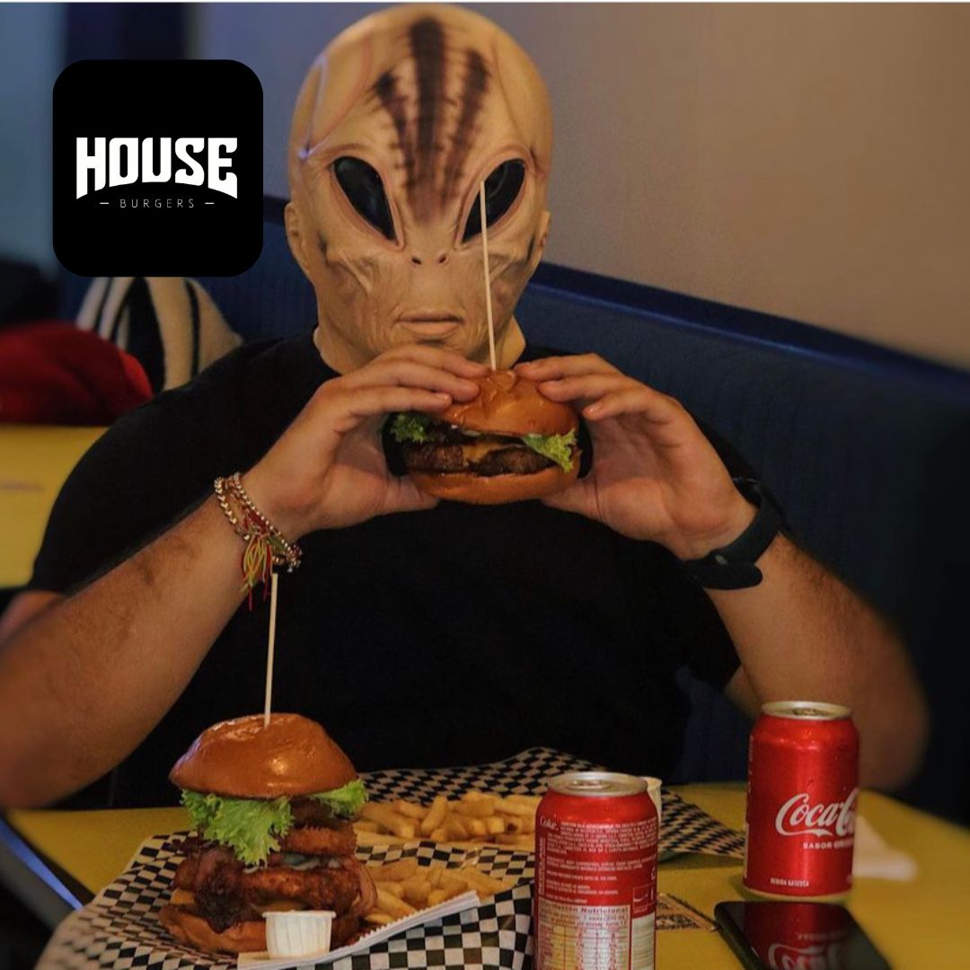 Restaurante con persona con mascara comiendo hamburguesa y gaseosa
