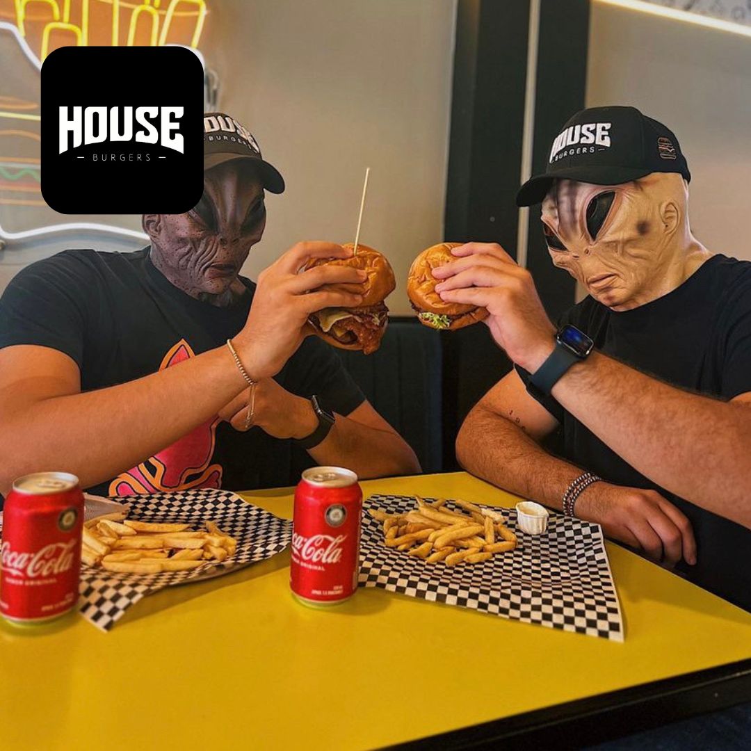 Restaurante con personas con mascaras comiendo hamburguesas papas y gaseosa
