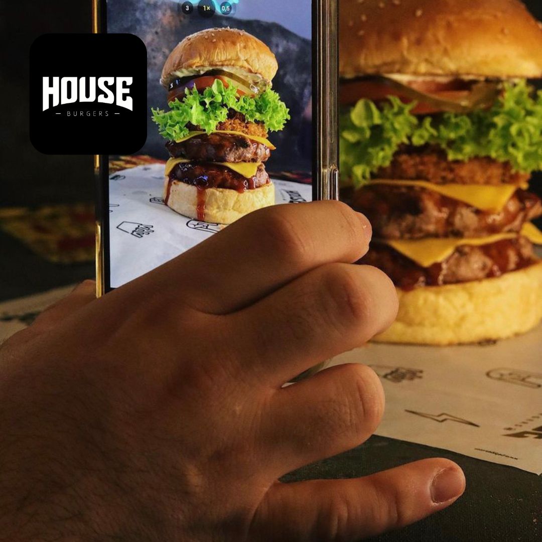 Restaurante con hamburguesa y celular tomando foto