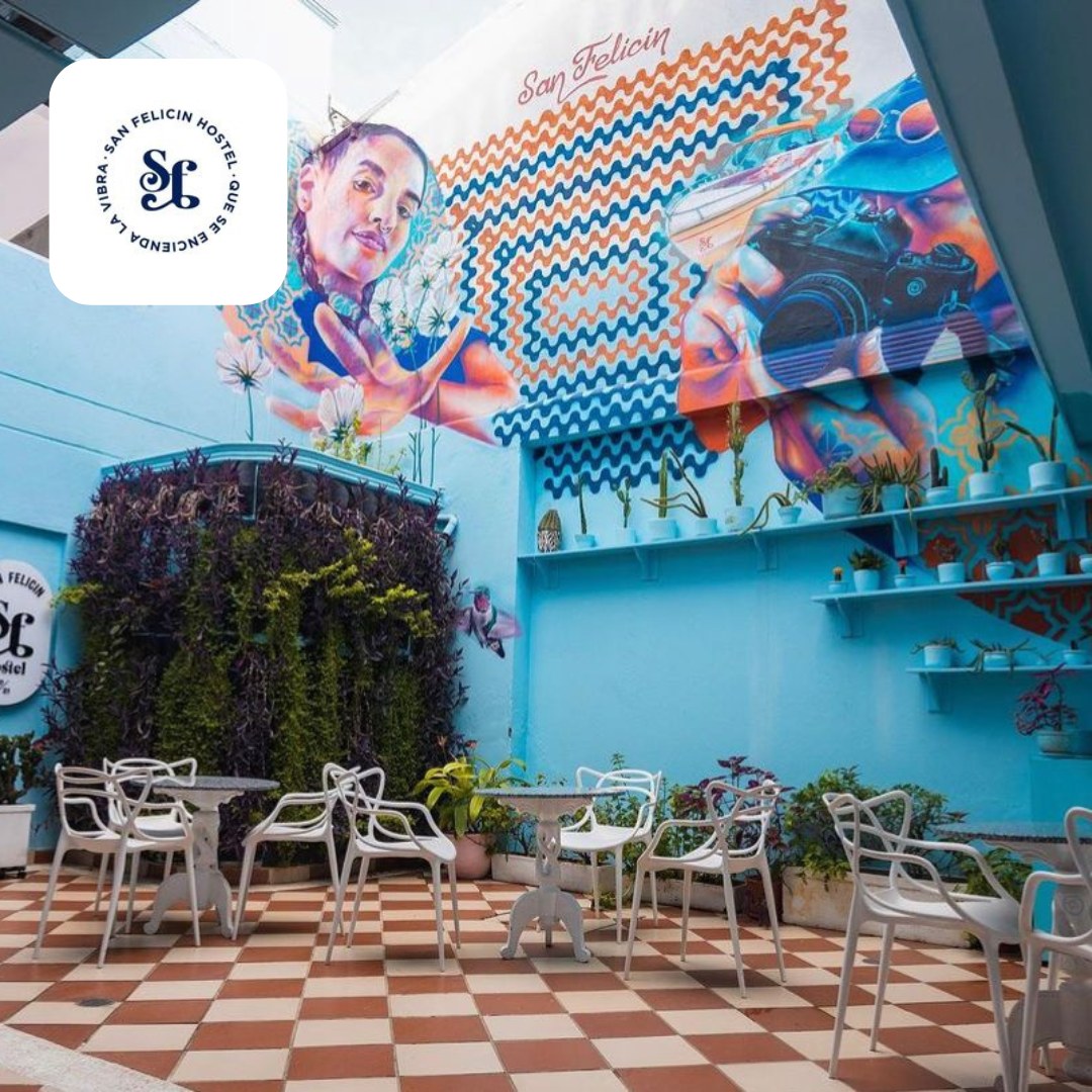 Bar con mesas blancas pared azul con mural y vegetación